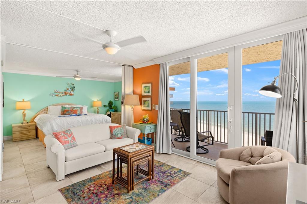 Bedroom with expansive windows, a water view, access to outside, a textured ceiling, and ceiling fan
