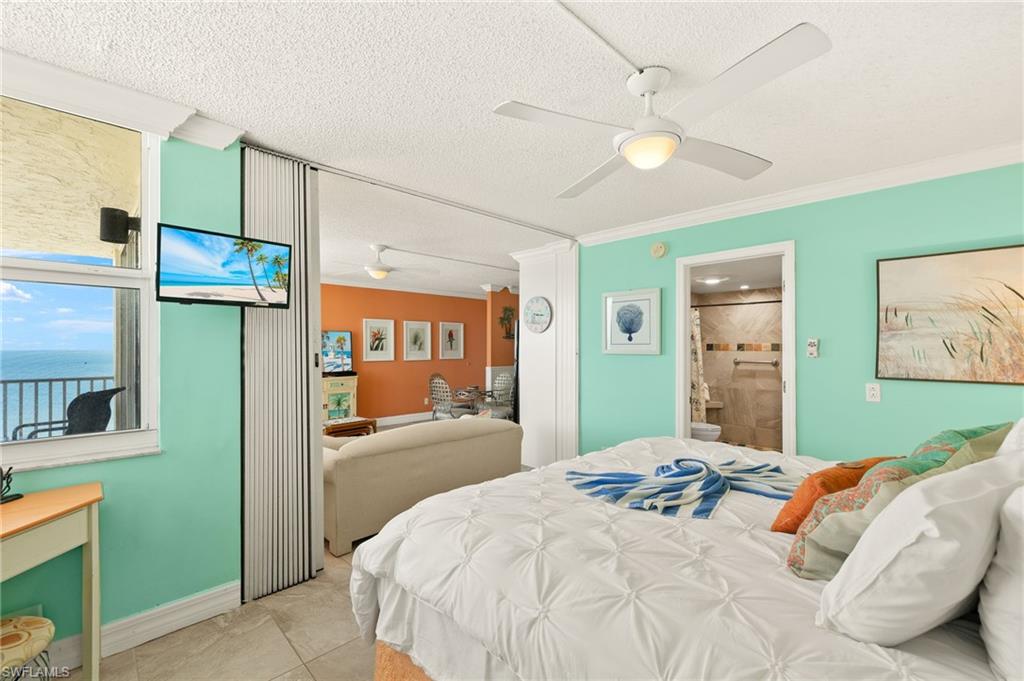 Bedroom featuring crown molding, a textured ceiling, a ceiling fan, connected bathroom, and light tile patterned floors