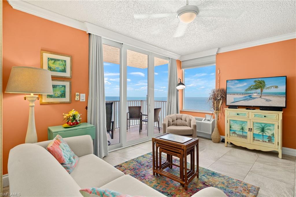 Living room with ornamental molding, a ceiling fan, and a textured ceiling