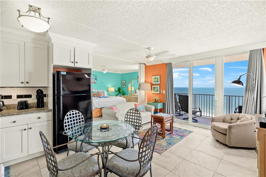 Dining space featuring expansive windows, a water view, a textured ceiling, a ceiling fan, and light tile patterned floors