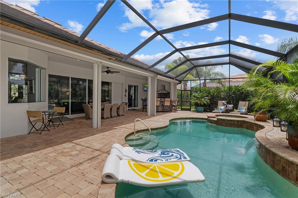 Integrated pool / spa featuring glass enclosure, a sunroom, a patio area, and an outdoor bar and dining area
