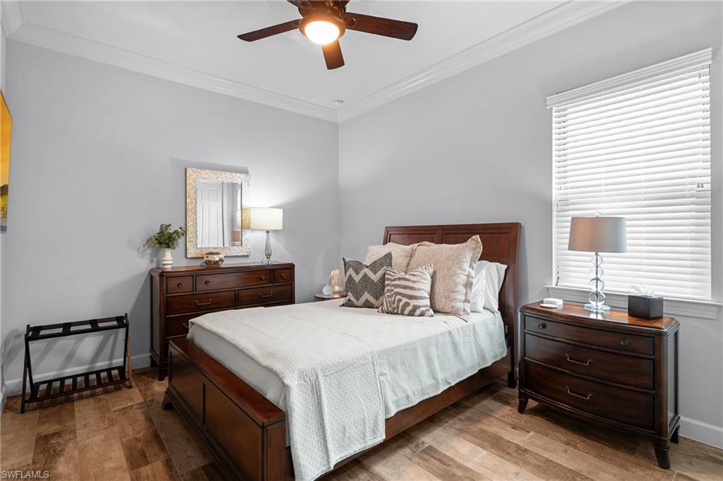Bedroom with hardwood / wood-style floors, crown molding, and a ceiling fan