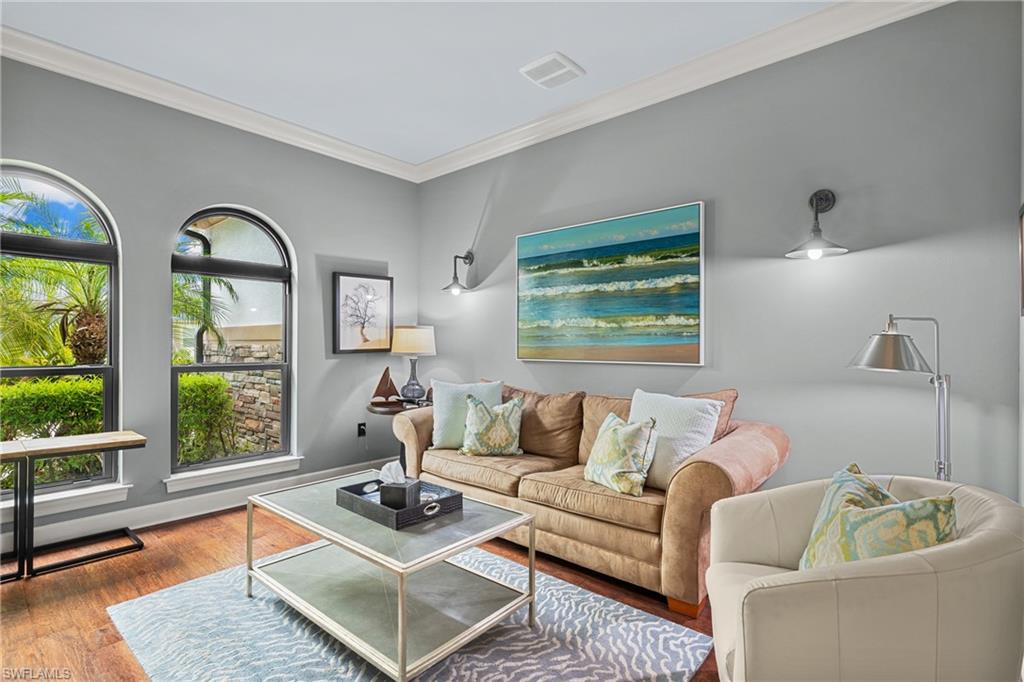 Den with crown molding and wood finished floors