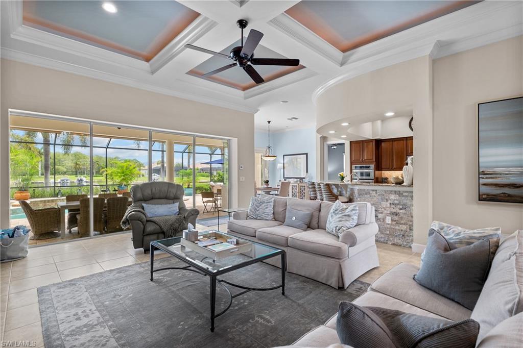 Living room with coffered ceiling, a ceiling fan, ornamental molding, recessed lighting, and light tile patterned floors