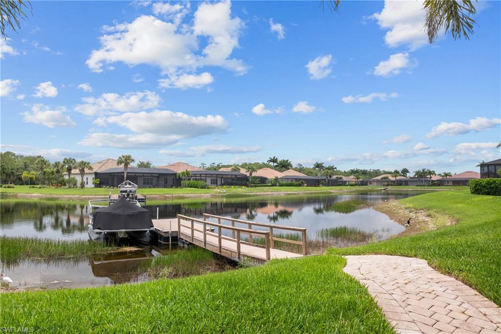 Private dock with a water view, a residential view, and a lawn