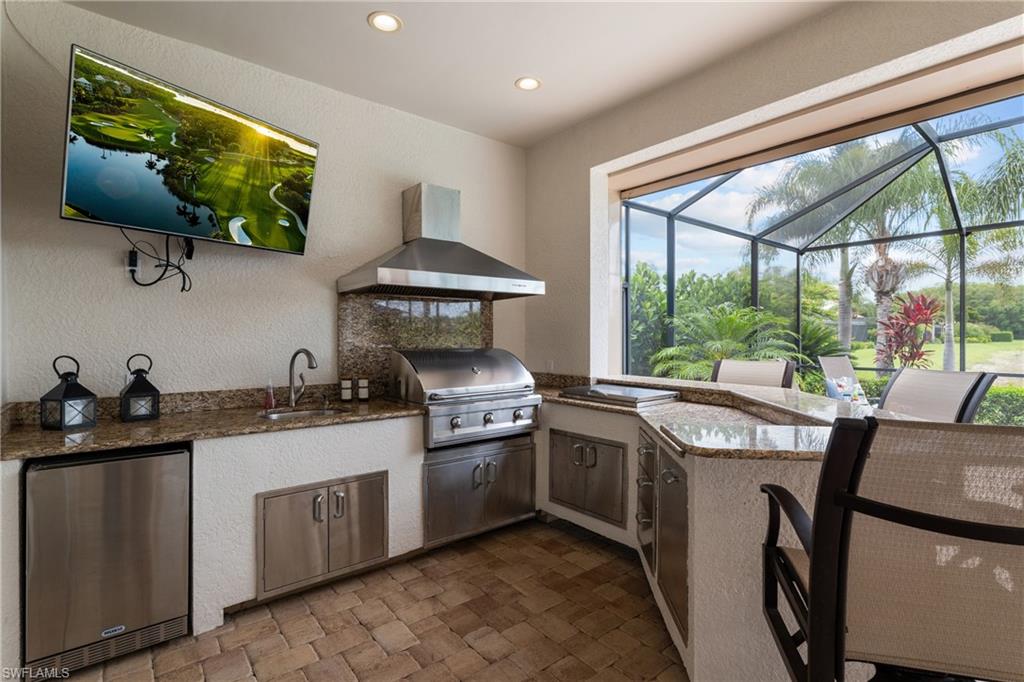 View of patio featuring glass enclosure, a sunroom, and exterior kitchen
