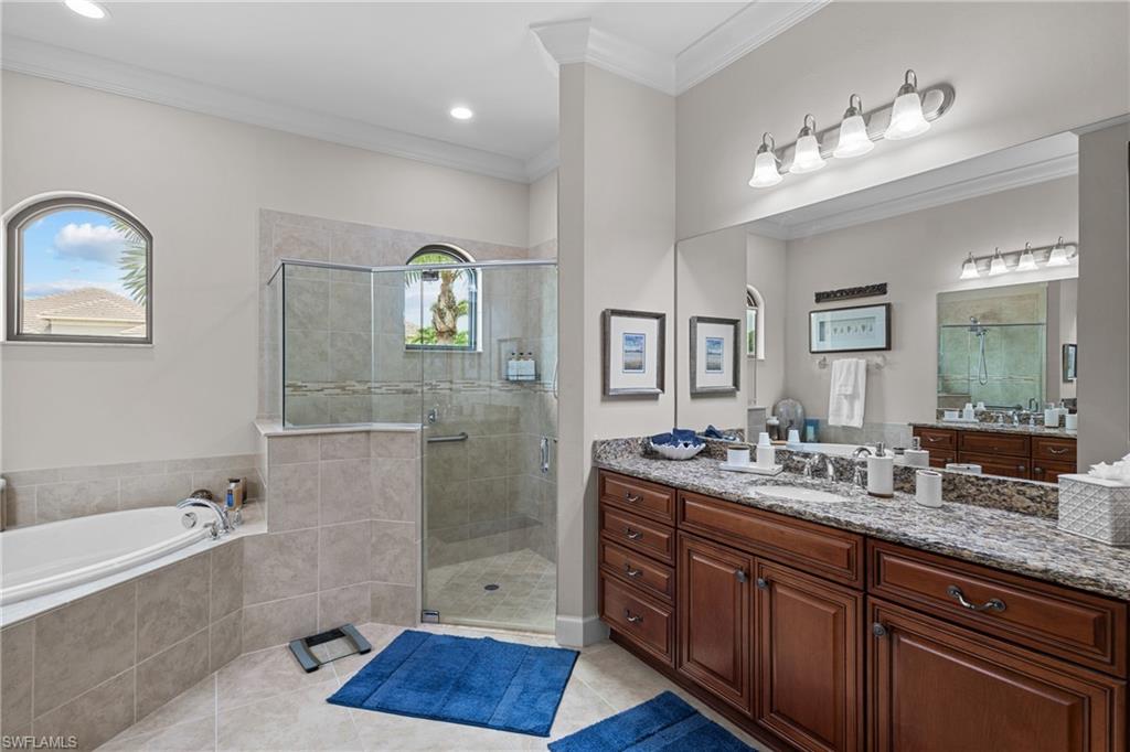 Full bath featuring vanity, a bath, a stall shower, light tile patterned flooring, and ornamental molding