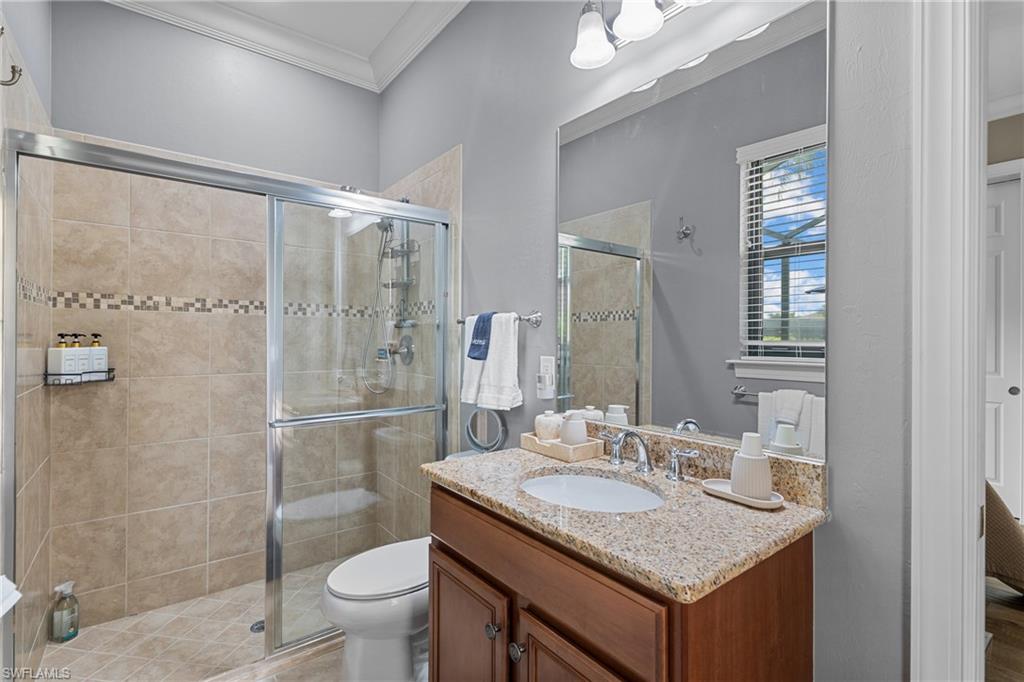 Bathroom with vanity, ornamental molding, and a stall shower