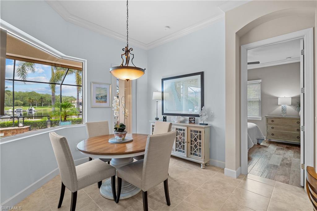 Dining room with crown molding, light tile patterned floors, and arched walkways