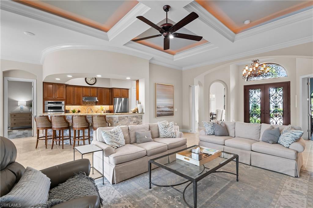 Living area featuring arched walkways, french doors, crown molding, coffered ceiling, and a ceiling fan