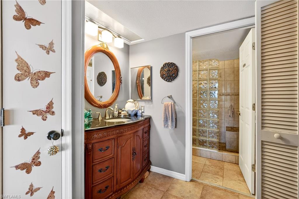 Full bathroom featuring vanity, a closet, a stall shower, and a textured ceiling