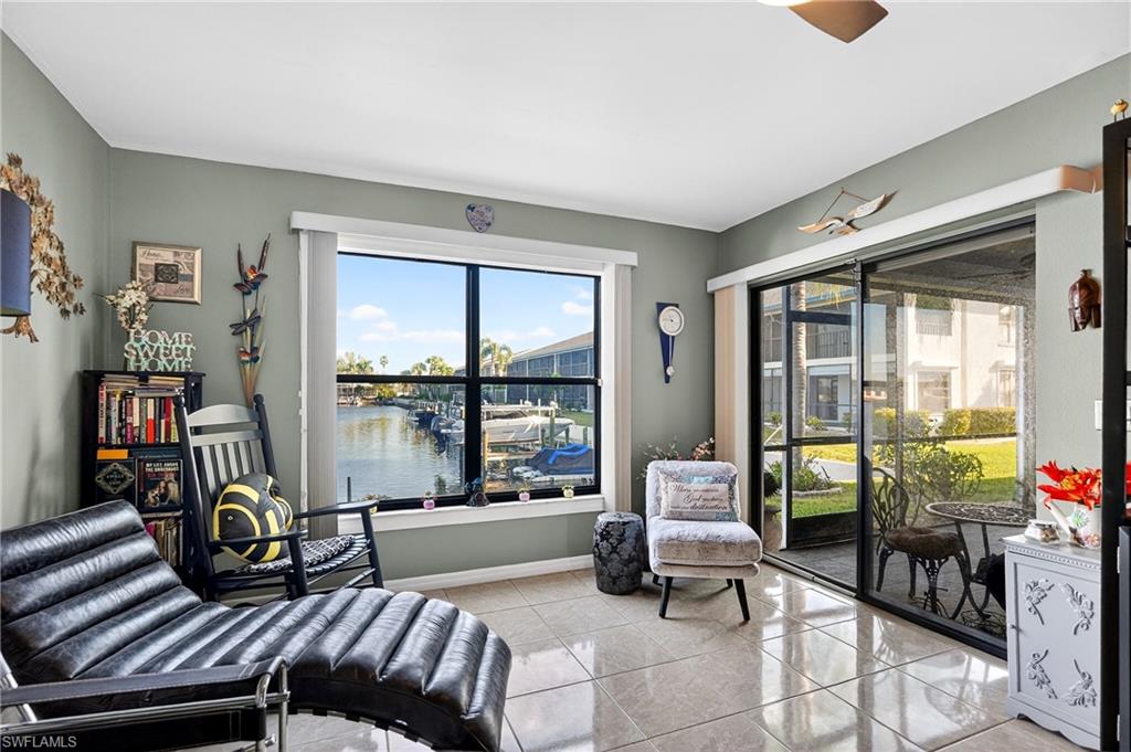 Living area featuring a water view, light tile patterned flooring, and ceiling fan