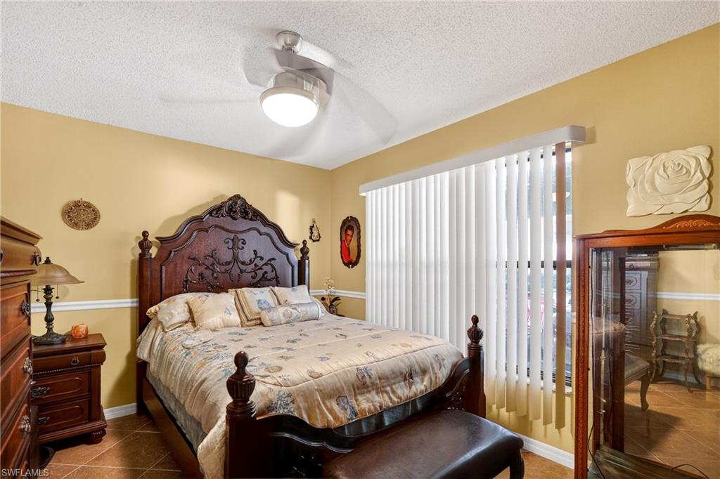 Tiled bedroom featuring ceiling fan and a textured ceiling