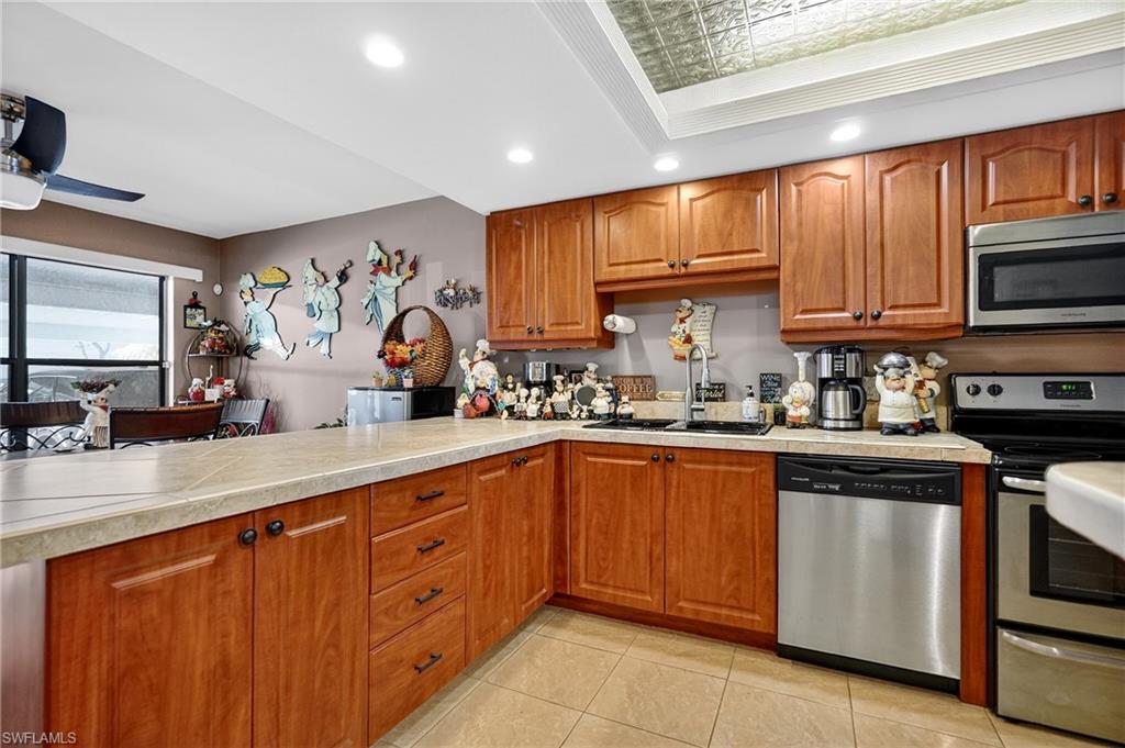Kitchen featuring wood finish cabinets, stainless steel appliances, an ornate ceiling, light countertops, and recessed lighting