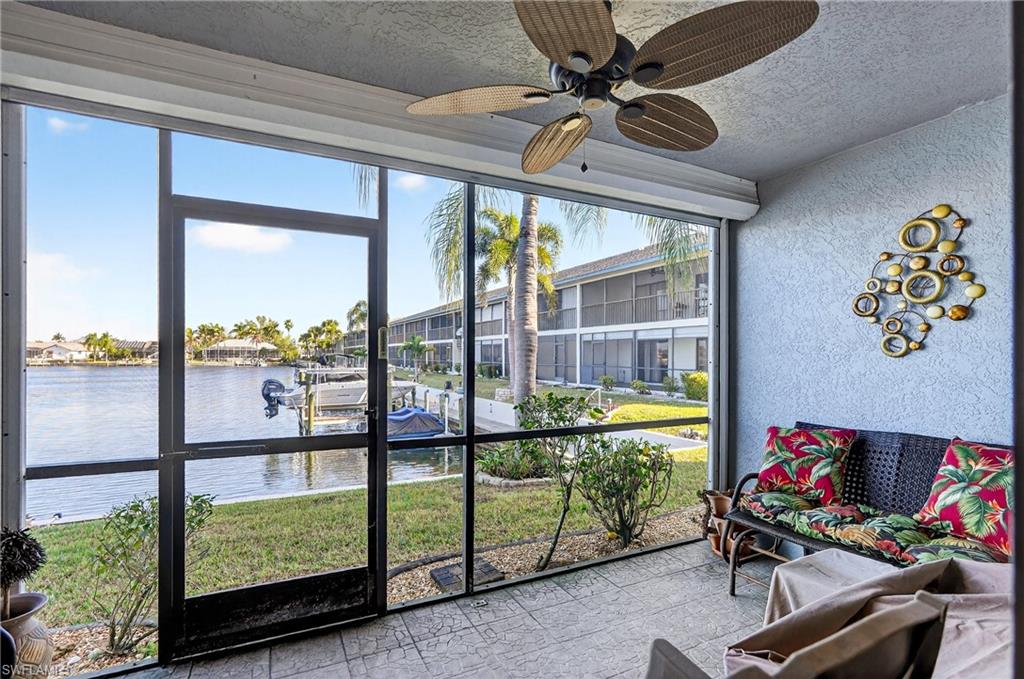 Sunroom with a textured wall, a textured ceiling, and a water view