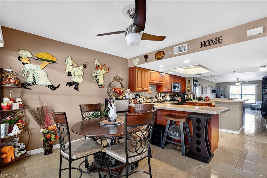 Dining area with ceiling fan, recessed lighting, light tile patterned flooring, and a tray ceiling