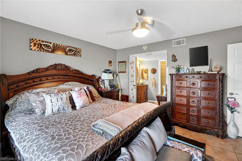 Bedroom with a ceiling fan, a textured ceiling, and ensuite bath