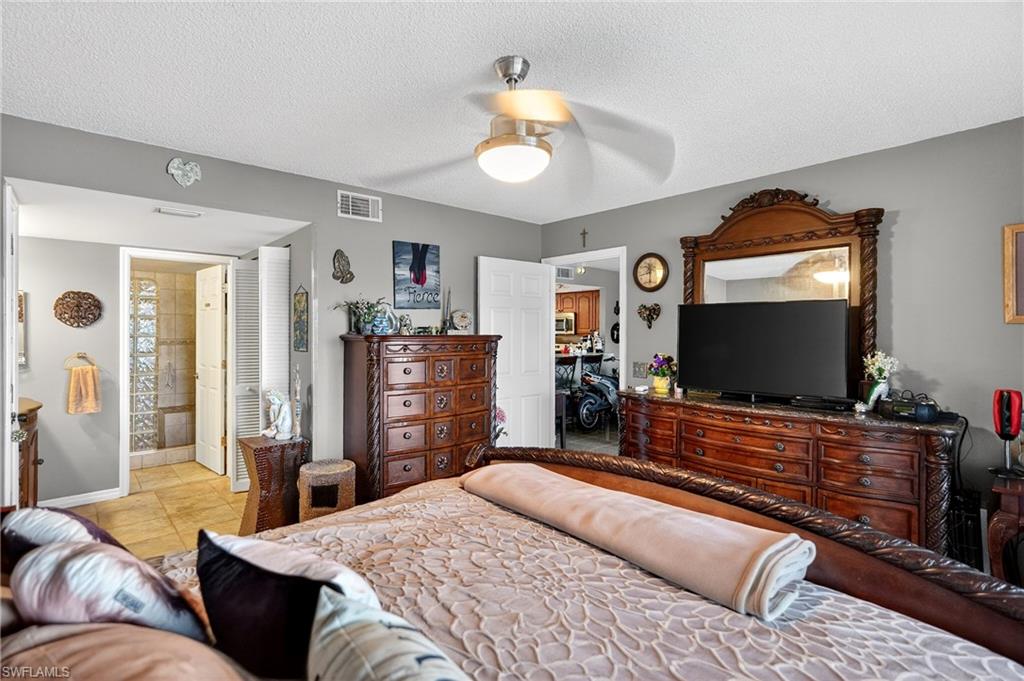 Bedroom featuring a textured ceiling, ceiling fan, and light tile patterned flooring