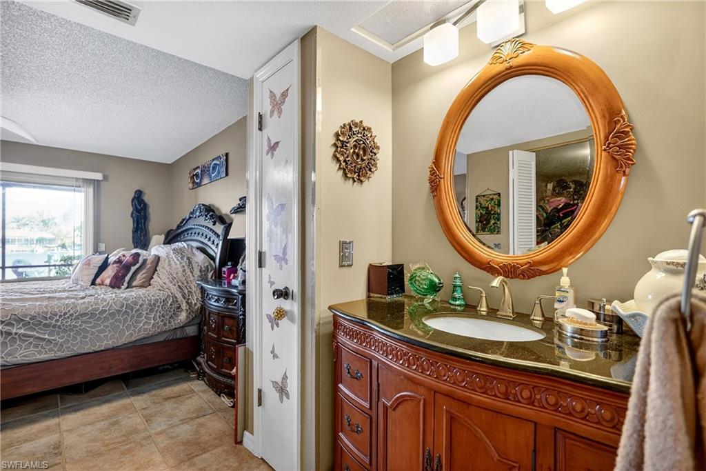 Ensuite bathroom with vanity, a textured ceiling, and light tile patterned floors