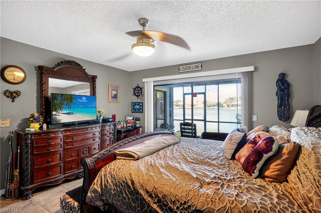 Bedroom featuring access to outside, a textured ceiling, ceiling fan, and light tile patterned floors