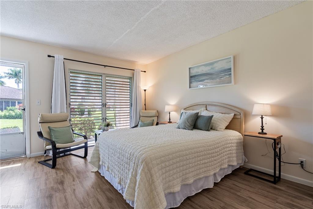 Bedroom featuring a textured ceiling, access to exterior, and wood finished floors