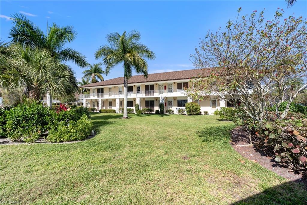 Rear view of property featuring a lawn, a balcony, and stucco siding