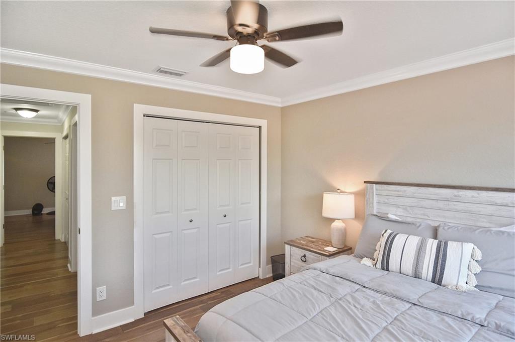 Bedroom featuring ornamental molding, dark wood finished floors, a closet, and ceiling fan