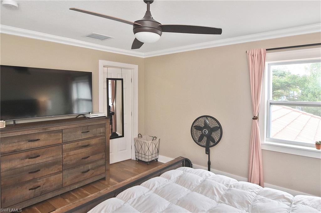 Bedroom featuring ceiling fan, dark wood-style flooring, and ornamental molding