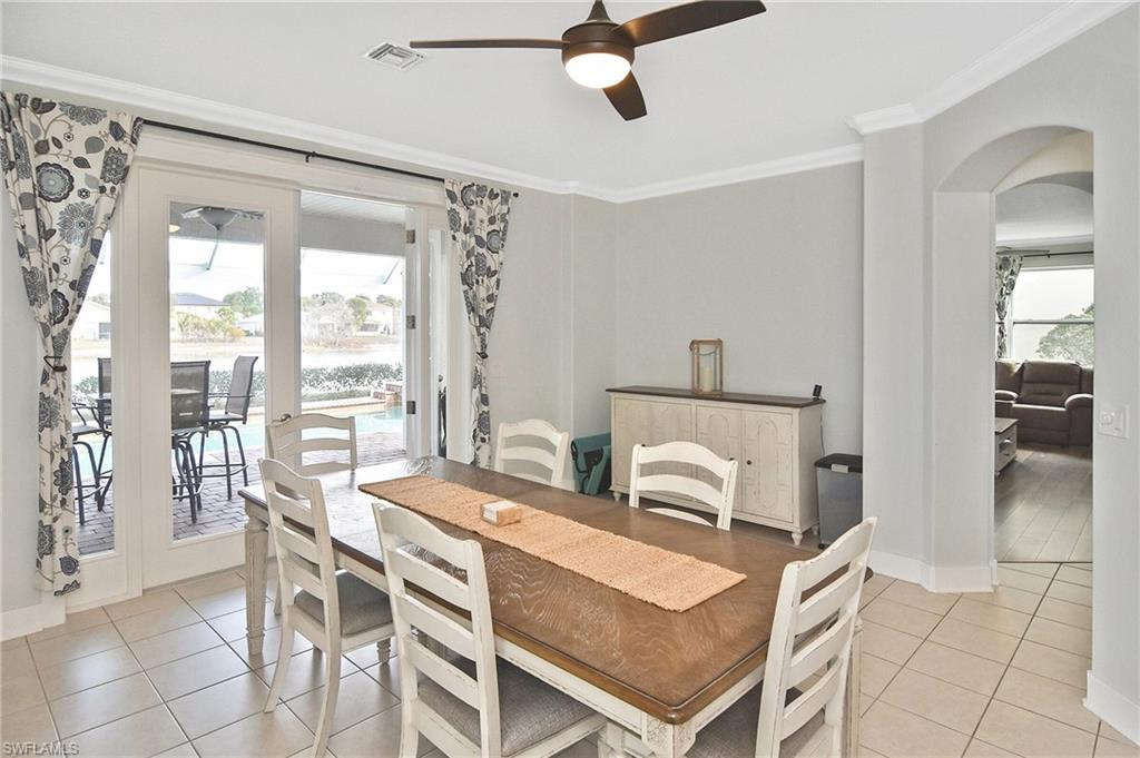 Dining space featuring a ceiling fan, crown molding, plenty of natural light, arched walkways, and light tile patterned floors