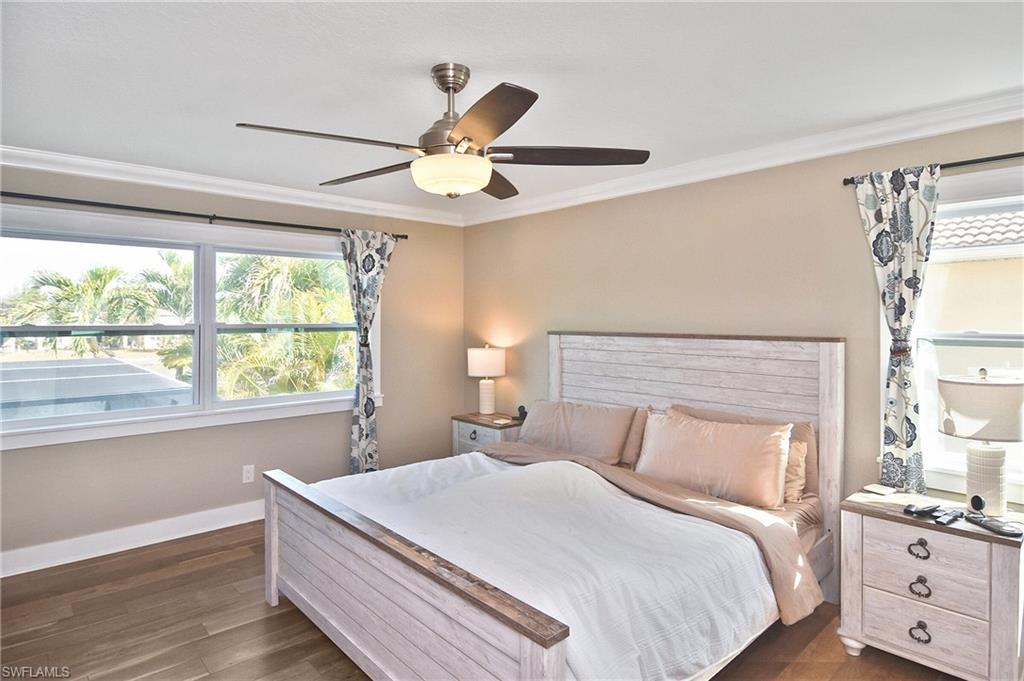 Bedroom with dark wood-style flooring, ceiling fan, and ornamental molding