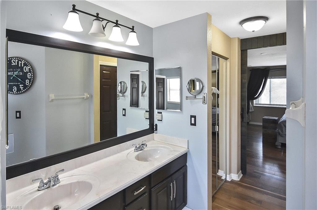 Full bath with double vanity and dark wood finished floors