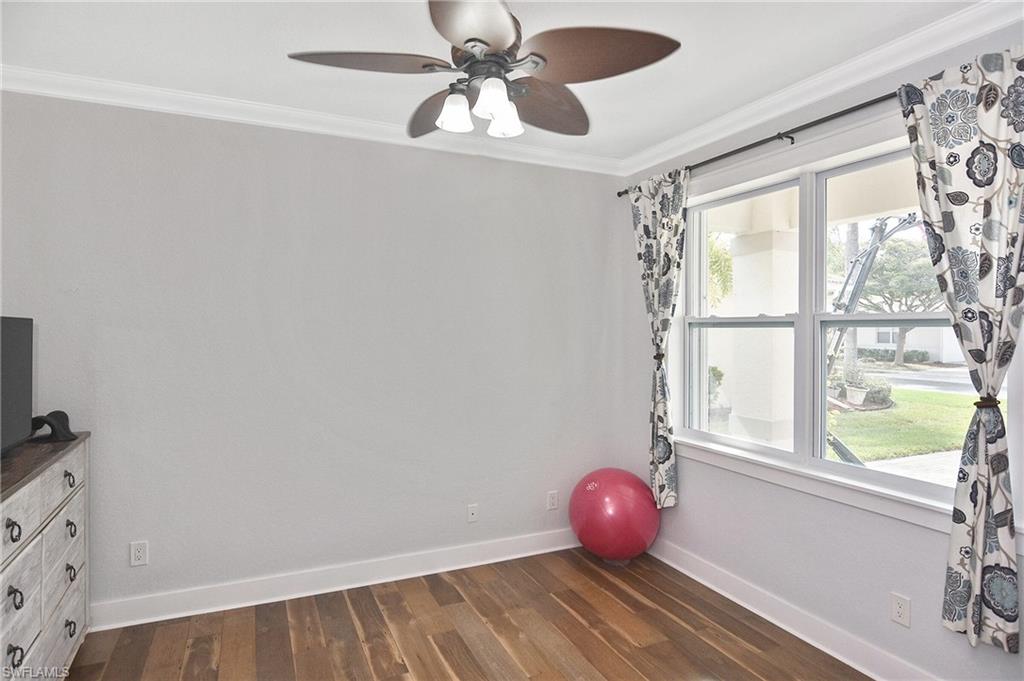 Workout room featuring dark wood-style floors, crown molding, and ceiling fan