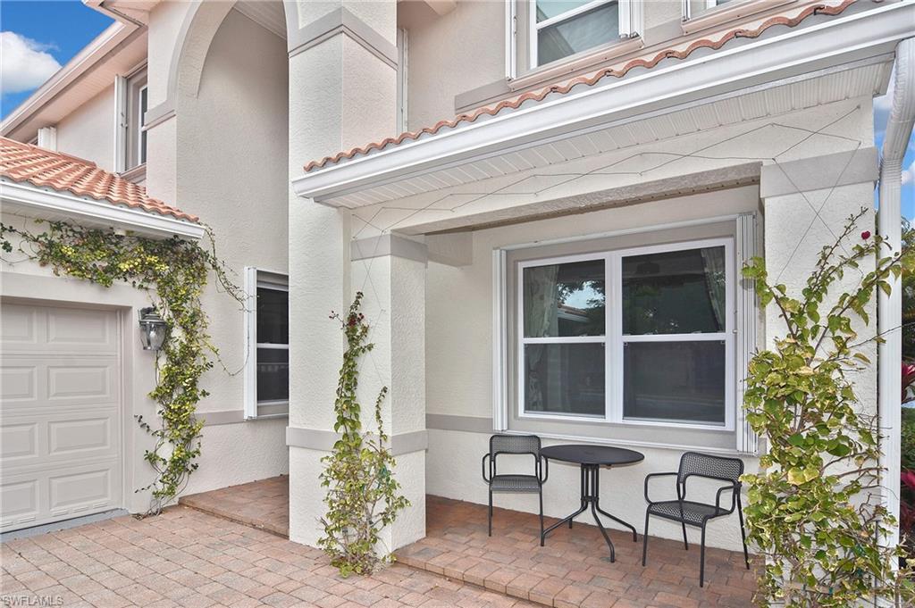 Property entrance with a tiled roof, stucco siding, a garage, and a patio area