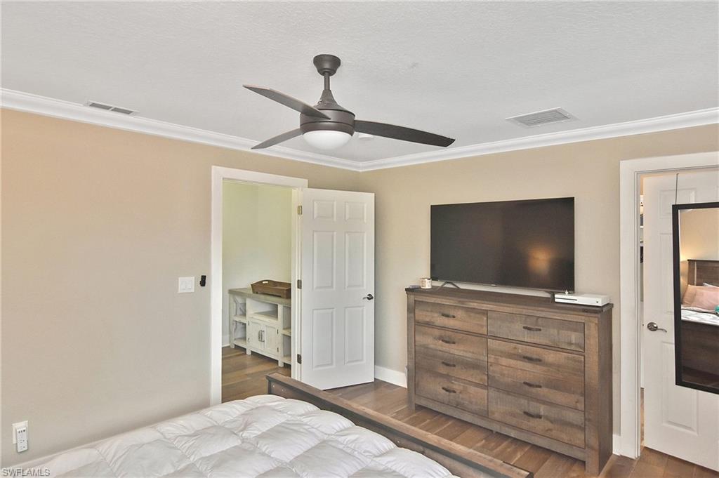 Bedroom featuring dark wood-style flooring, a ceiling fan, and crown molding