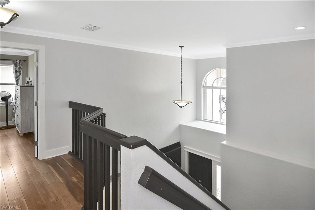 Corridor featuring crown molding, an upstairs landing, and dark wood-style flooring