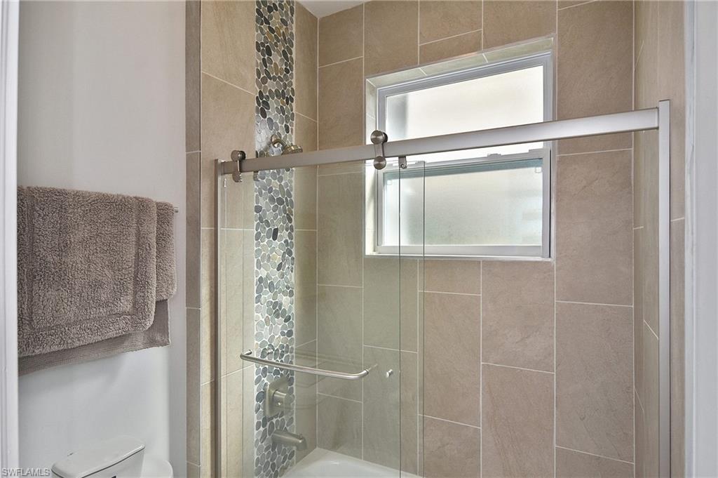 Bathroom featuring bath / shower combo with glass door and toilet