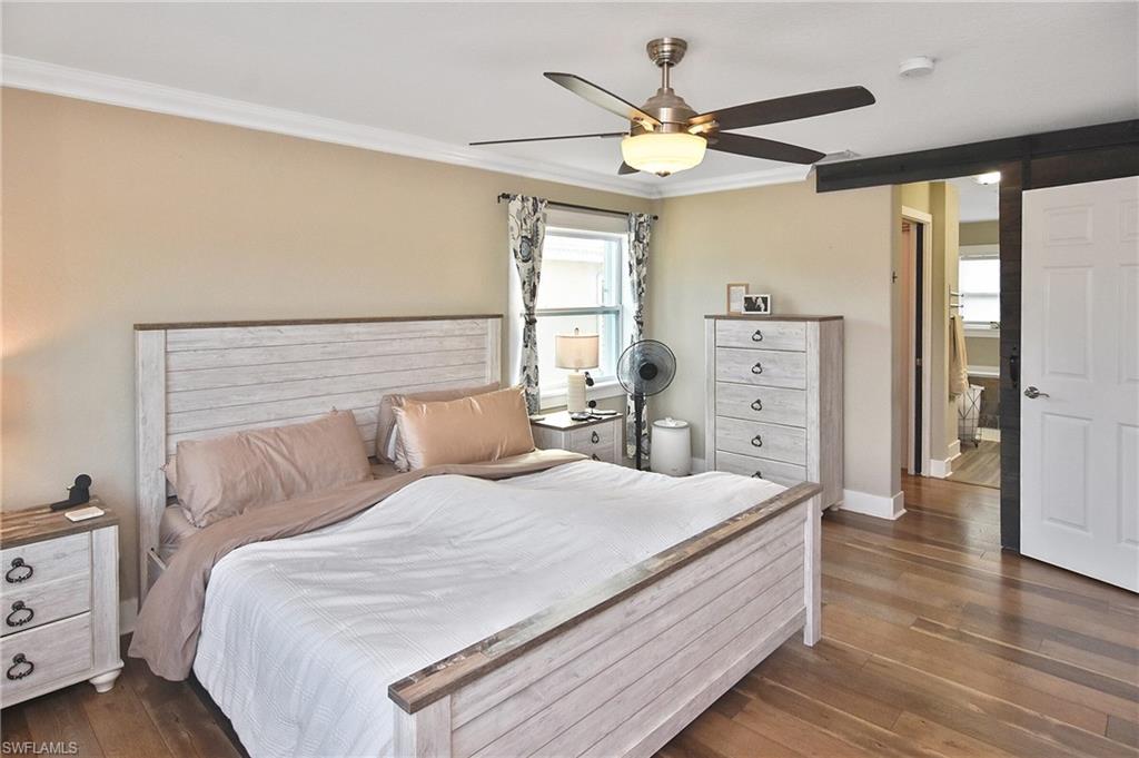 Bedroom with crown molding, ceiling fan, and dark wood-style floors