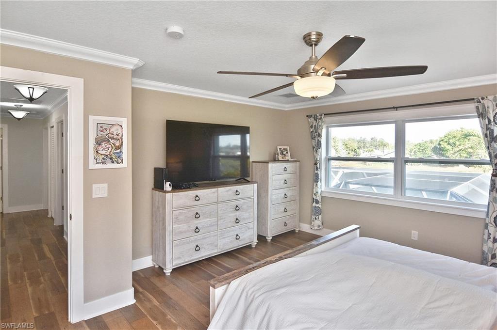 Bedroom featuring dark wood-style floors, ornamental molding, and a ceiling fan