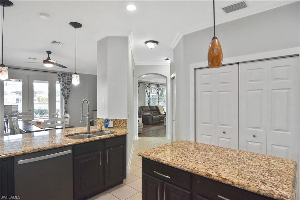 Kitchen with pendant lighting, ceiling fan, dishwasher, light stone counters, and ornamental molding