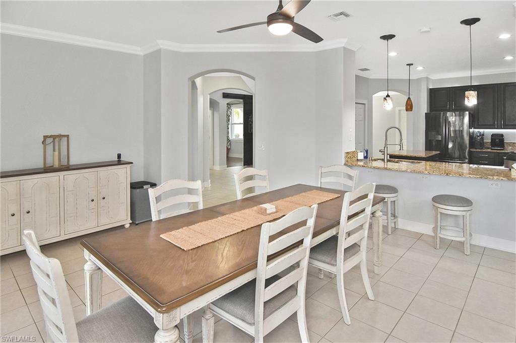Dining space with ornamental molding, light tile patterned floors, arched walkways, ceiling fan, and recessed lighting