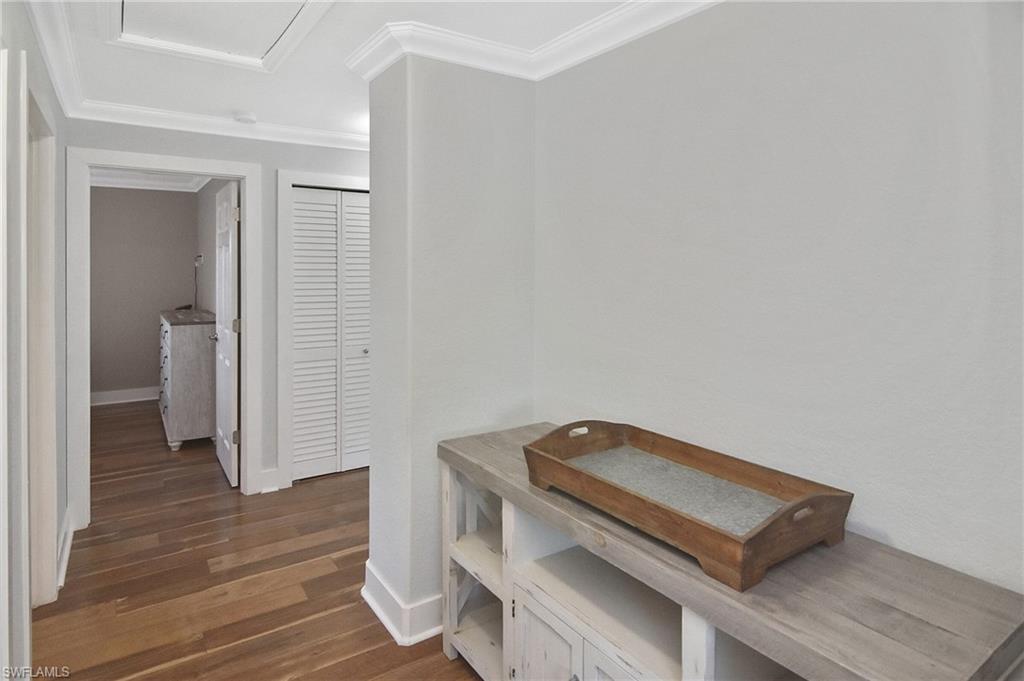 Corridor featuring dark wood-style flooring and crown molding
