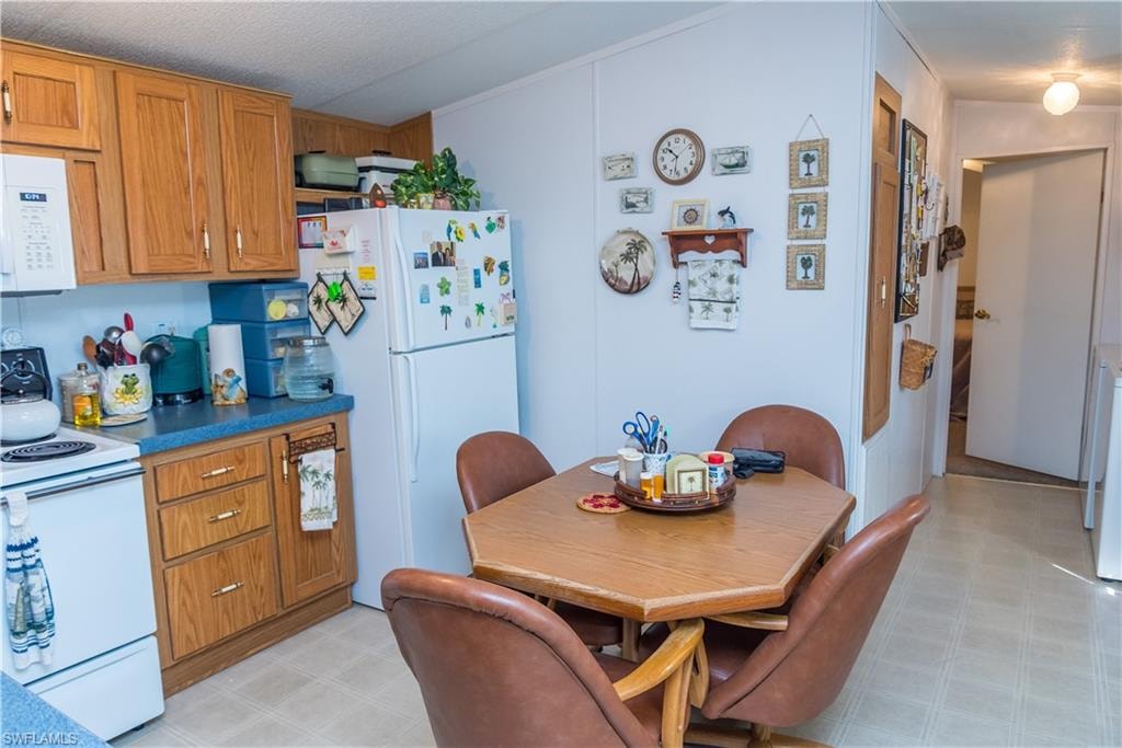 Kitchen with wood finish cabinets, white appliances, and light floors