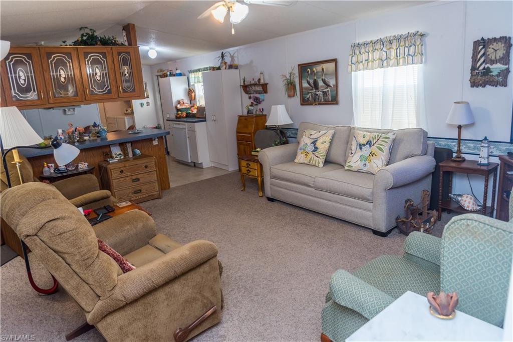 Living area with ceiling fan and light carpet