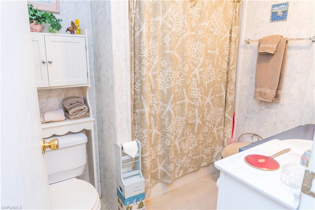 Bathroom with vanity, wallpapered walls, and shower / bath combo