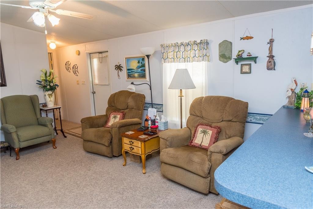 Carpeted living area with ceiling fan
