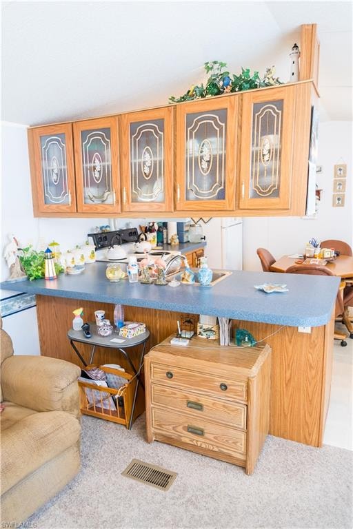 Kitchen with glass fronted cabinets, a kitchen breakfast bar, stove, wood finish cabinetry, and light carpet