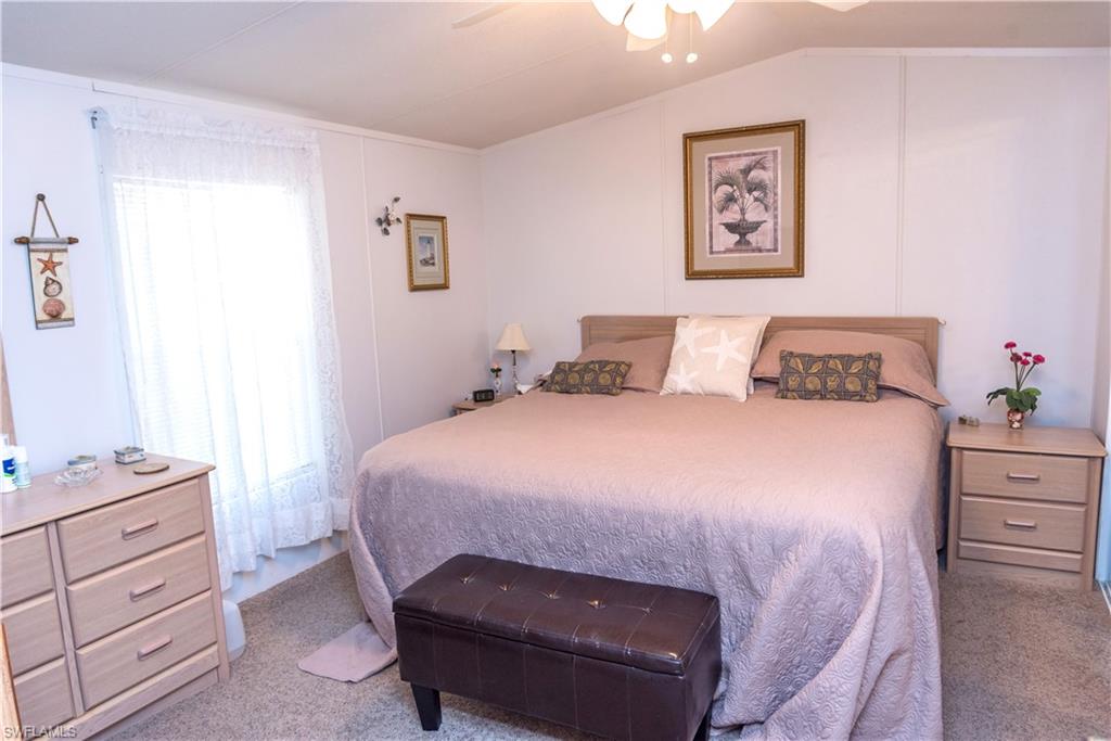 Carpeted bedroom with ceiling fan and vaulted ceiling