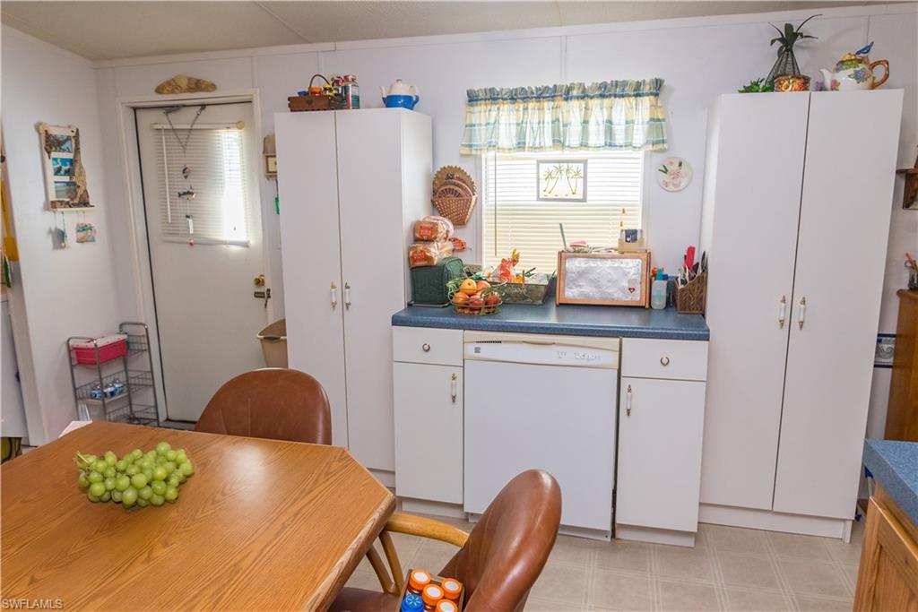 Kitchen with dishwasher, dark countertops, white cabinets, and light floors