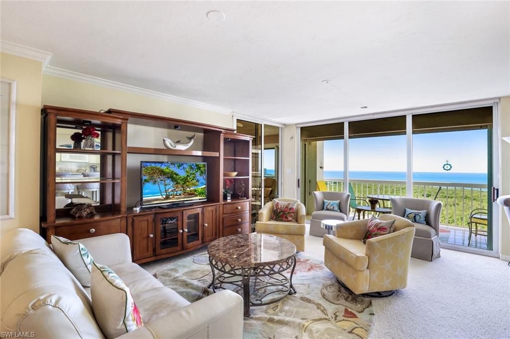 Living area with expansive windows, light carpet, and crown molding
