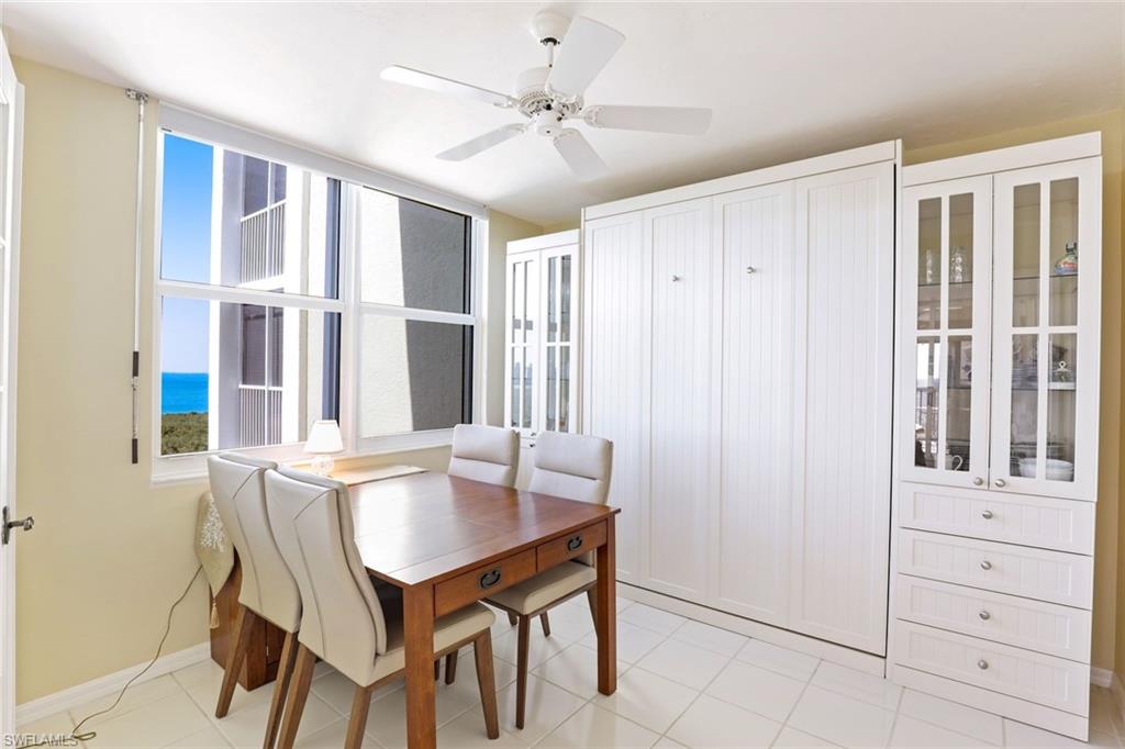 Dining space with ceiling fan, a water view, and light tile patterned floors